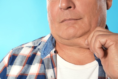 Mature man with double chin on blue background, closeup