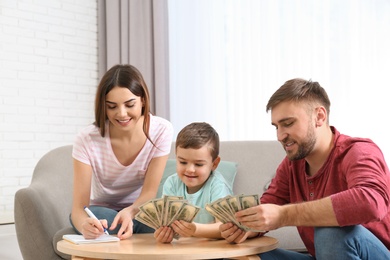 Happy family with money at table indoors