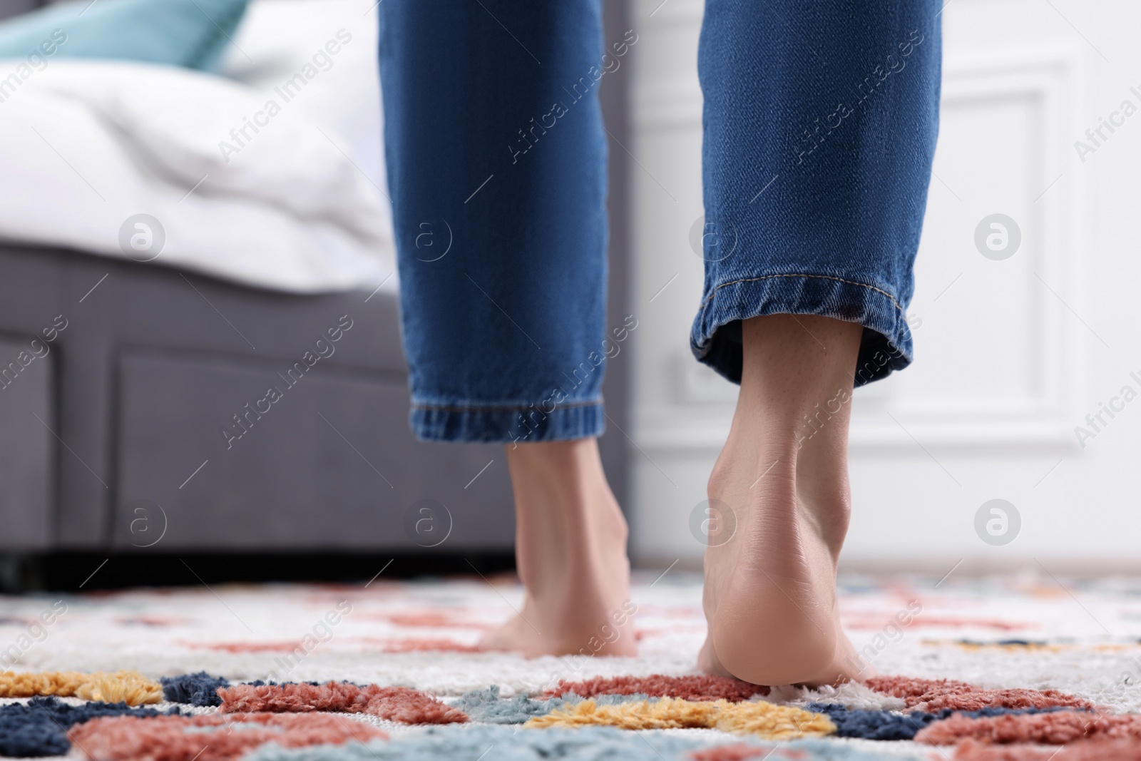 Photo of Woman walking on carpet with pattern at home, closeup