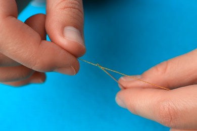 Photo of Closeup view of woman threading sewing needle