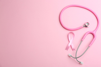 Photo of Pink ribbon and stethoscope on color background, flat lay with space for text. Breast cancer concept