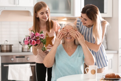 Photo of Young woman with daughter congratulating mature family member at home. Happy Mother's Day