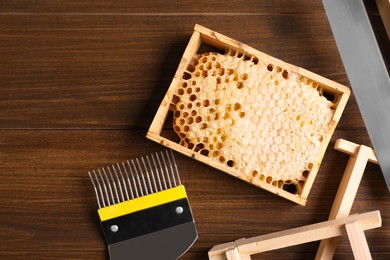 Honeycomb frames and beekeeping tools on wooden table, flat lay