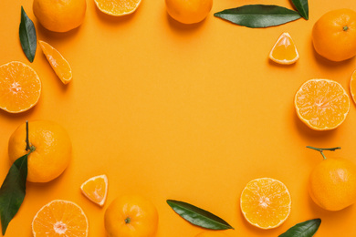 Photo of Frame made of fresh ripe tangerines and space for text on orange background, flat lay. Citrus fruit