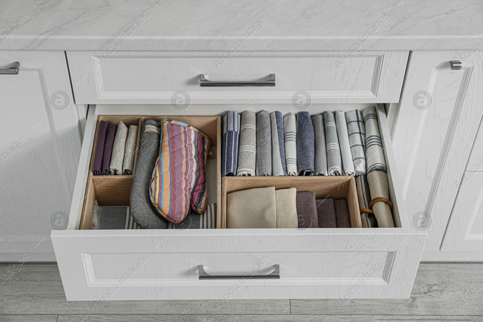 Photo of Open drawer with different textiles in kitchen