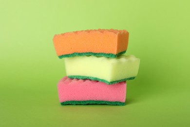 Three stacked cleaning sponges on green background