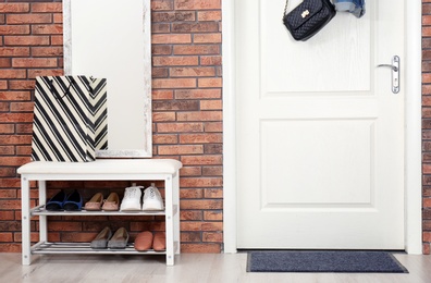 Photo of Hallway interior with shoe rack, mirror and mat near door