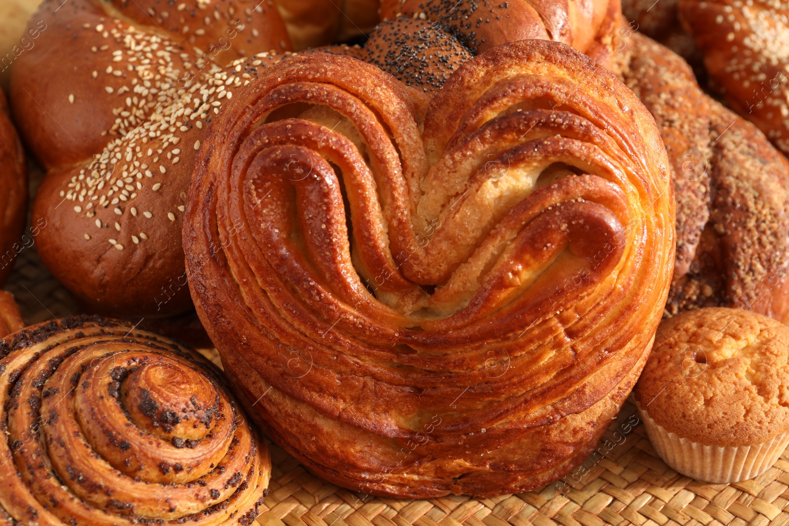 Photo of Different tasty freshly baked pastries on wicker mat, closeup