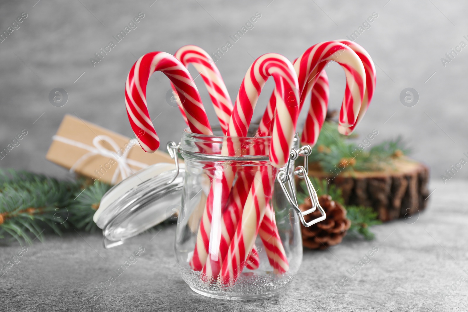 Photo of Christmas candy canes in glass jar on grey table