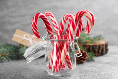 Photo of Christmas candy canes in glass jar on grey table