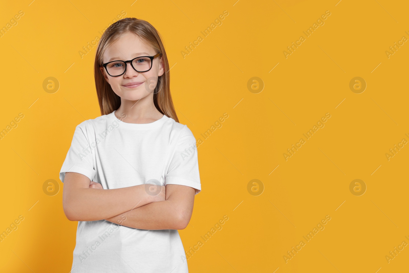 Photo of Portrait of cute girl in glasses on orange background. Space for text