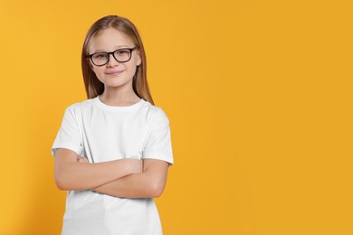 Portrait of cute girl in glasses on orange background. Space for text