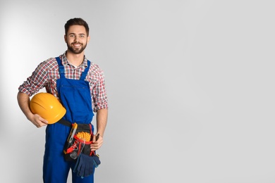 Photo of Portrait of construction worker with tool belt on light background. Space for text