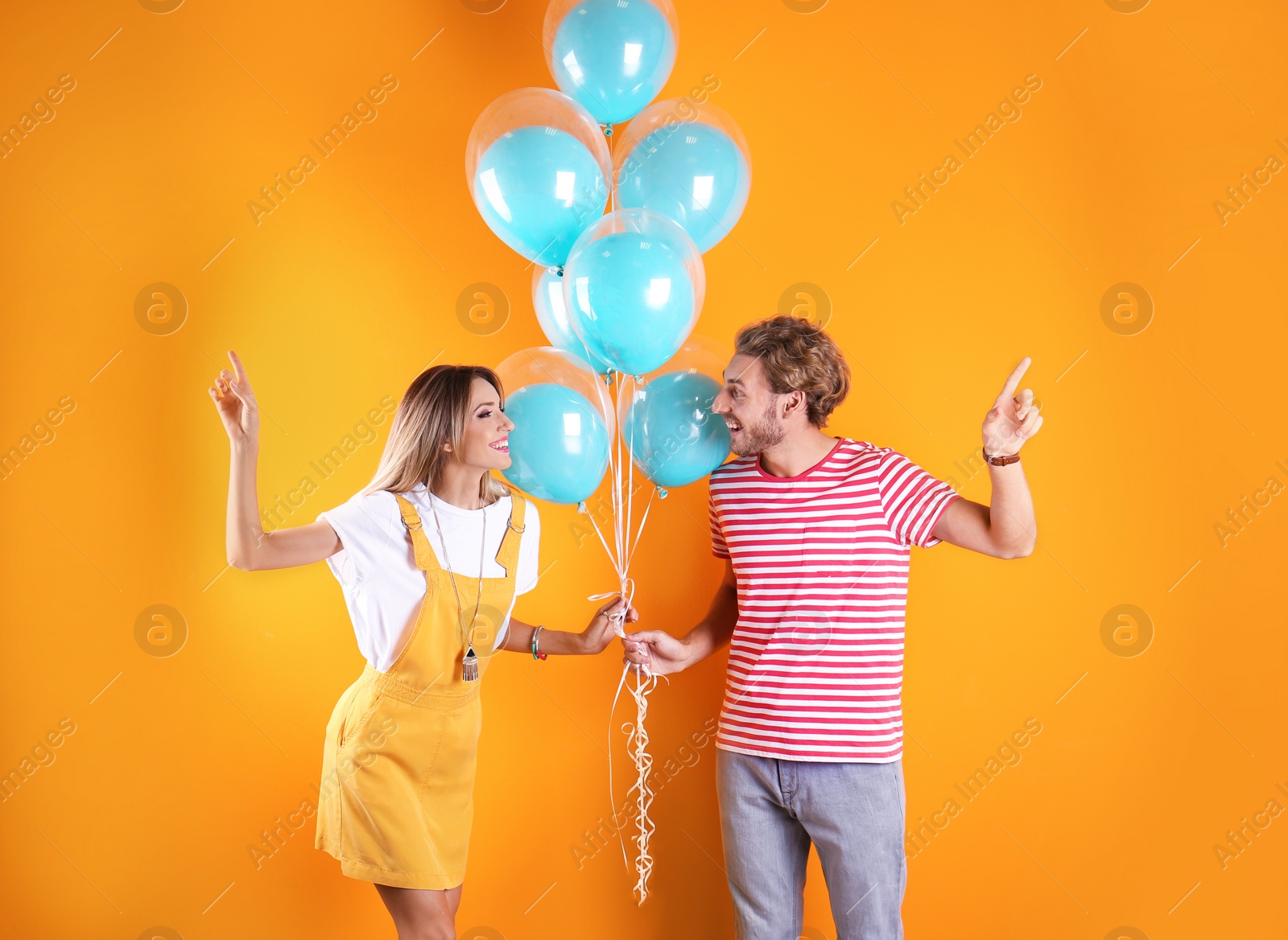 Photo of Young couple with air balloons on color background