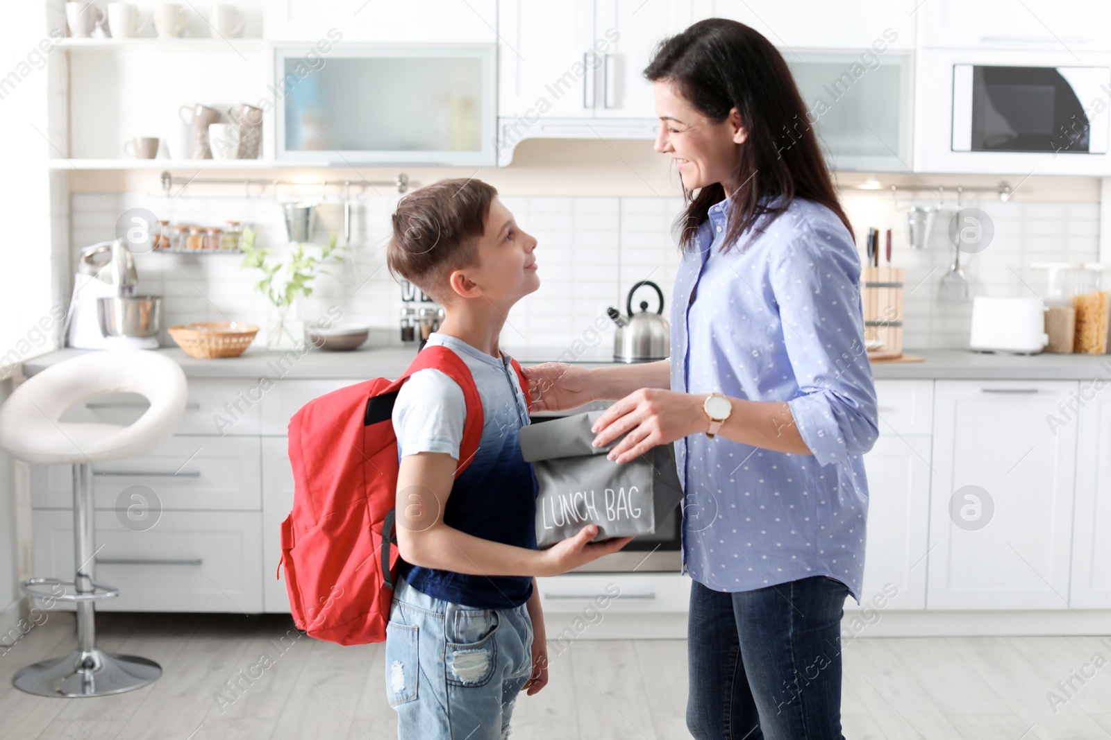 Photo of Young woman helping her little child get ready for school at home