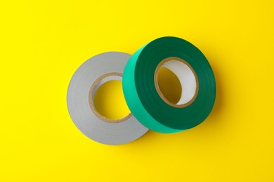 Photo of Colorful insulating tapes on yellow background, flat lay