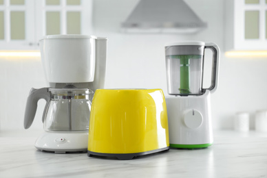 Set of modern home appliances on white marble table in kitchen