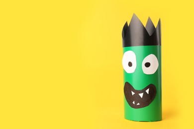 Photo of Funny green monster on yellow background, space for text. Halloween decoration