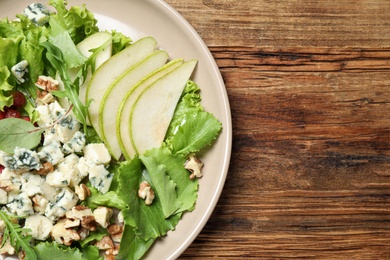 Photo of Fresh salad with pear on wooden table, top view. Space for text