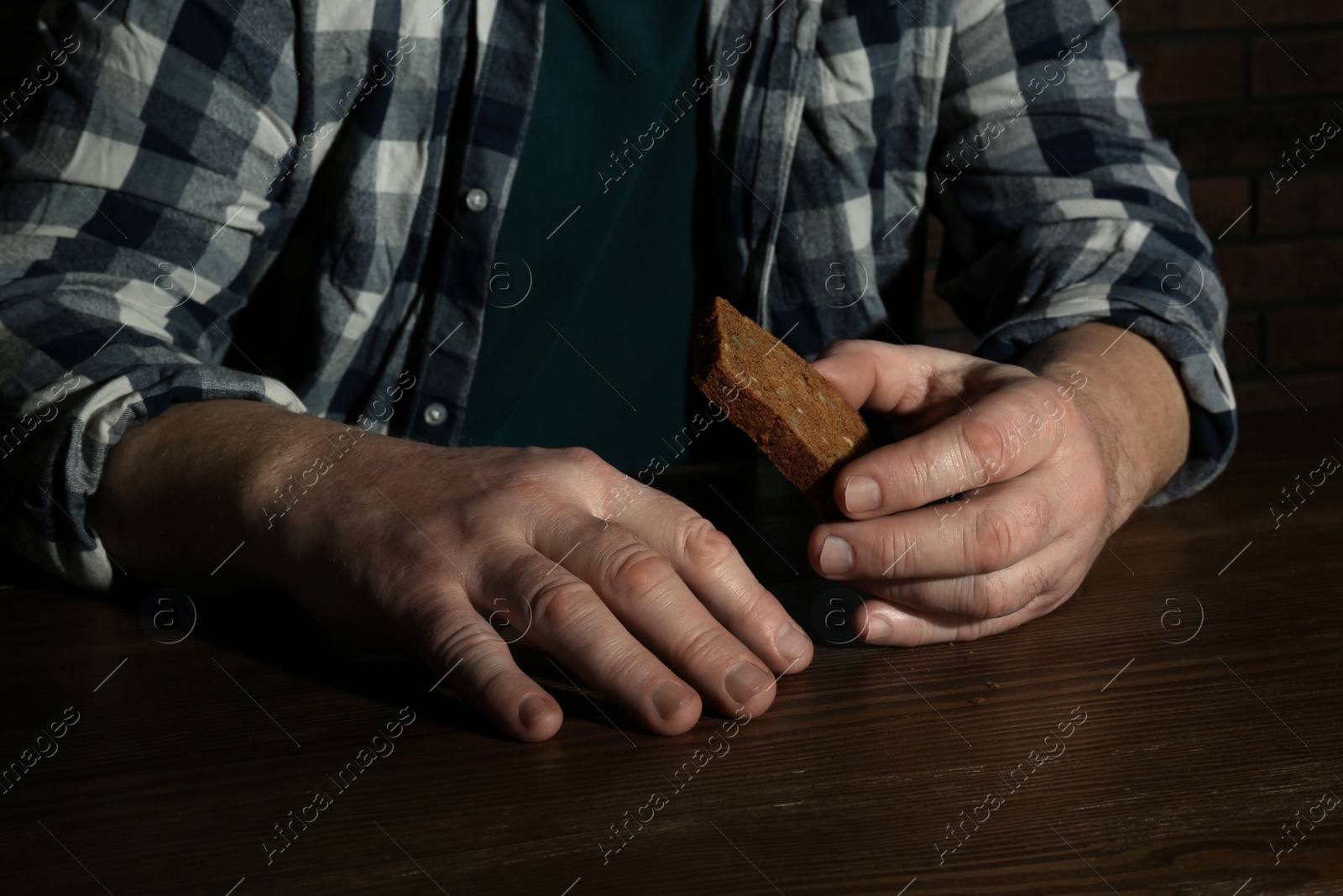 Photo of Poor senior man with bread at table, closeup