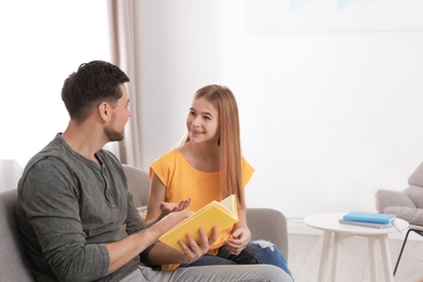 Father and his teenager daughter with book at home