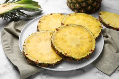 Photo of Slices of tasty ripe pineapple on white marble table, closeup