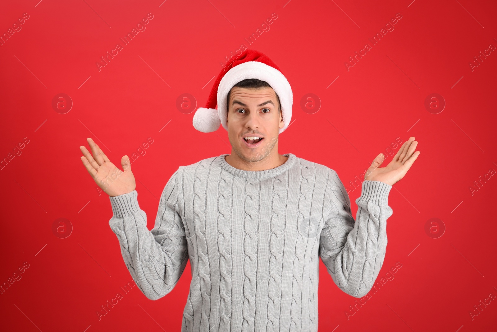 Photo of Surprised man wearing Santa hat on red background