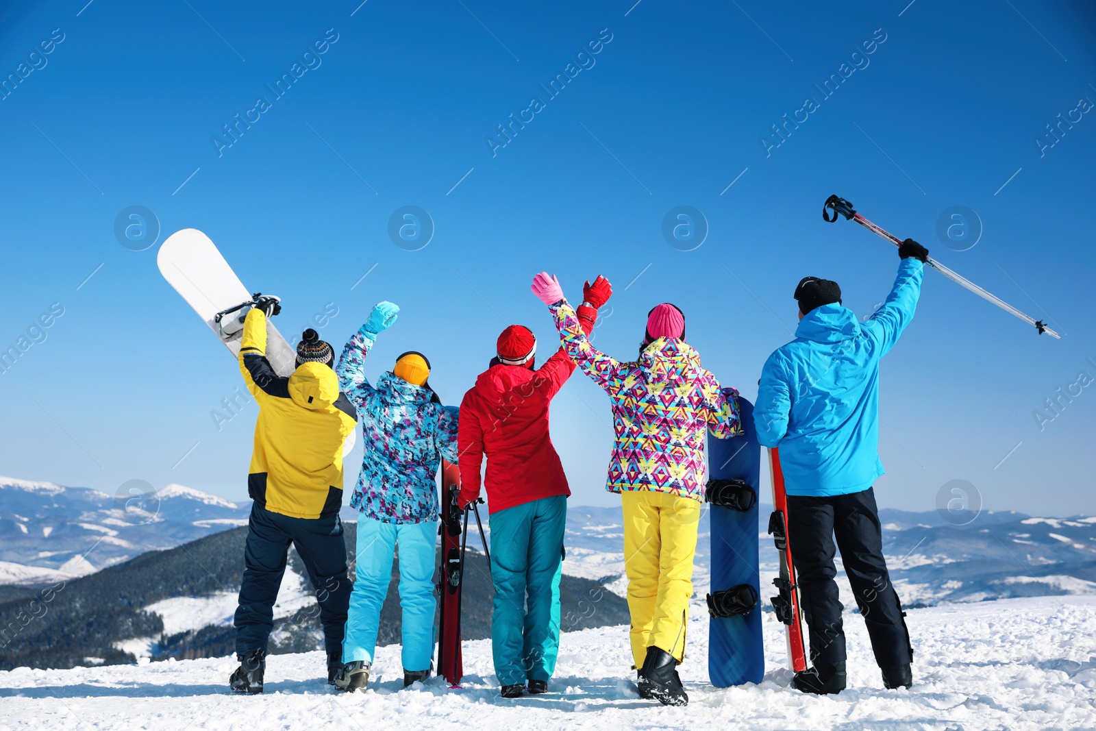 Photo of Group of friends with equipment at ski resort, back view. Winter vacation