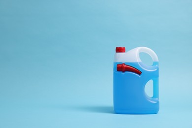 Photo of Plastic canister with color liquid on light blue background. Space for text