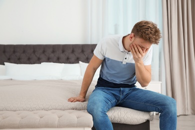 Photo of Young man having nausea in bedroom. Space for text