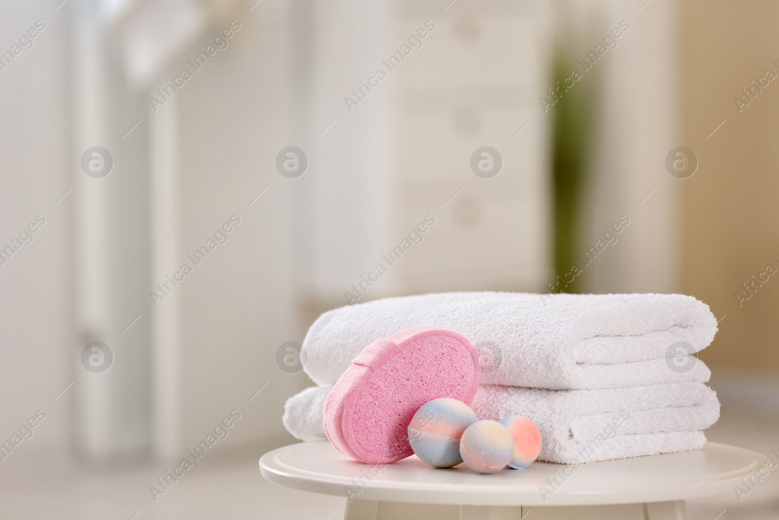 Photo of Clean towels and toiletries on table against blurred background