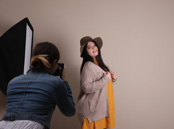 Photographer taking picture of overweight woman on beige background. Plus size model
