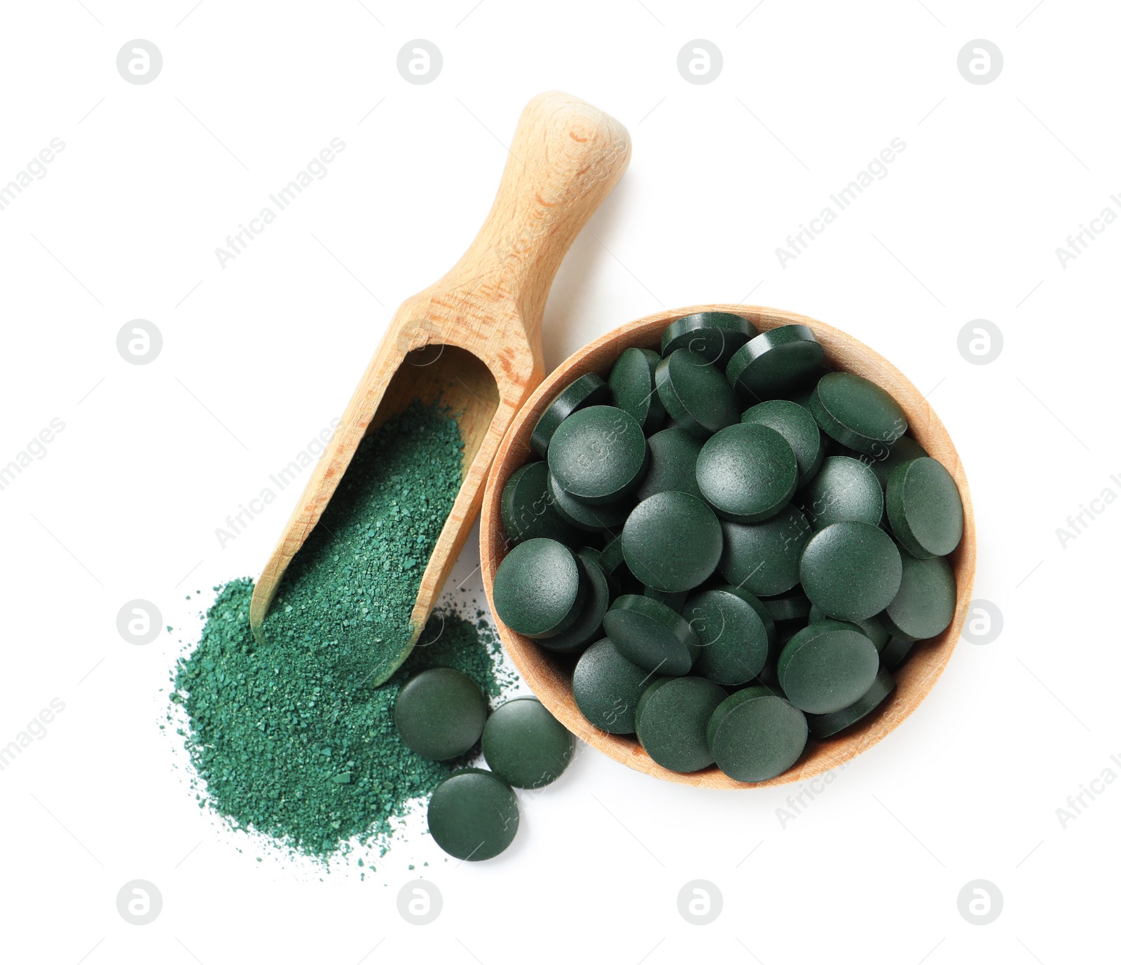 Photo of Wooden bowl of spirulina pills and powder in scoop on white background, top view