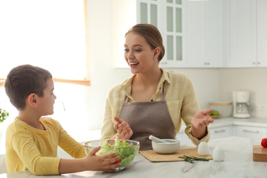 Mother and son cooking salad together in kitchen