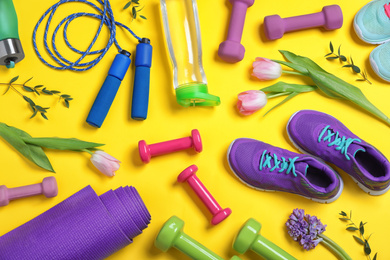 Photo of Flat lay composition with spring flowers and sports items on yellow background