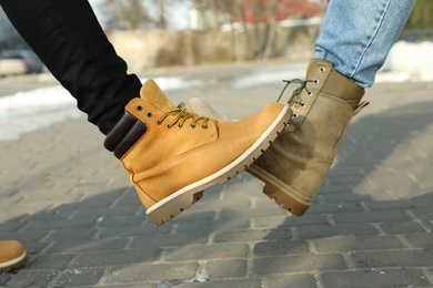 Photo of Men greeting each other by bumping feet outdoors, closeup