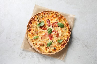 Tasty quiche with cheese and tomatoes on light grey table, top view