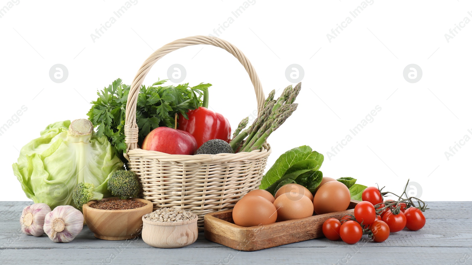 Photo of Healthy food. Basket with different fresh products on grey wooden table against white background