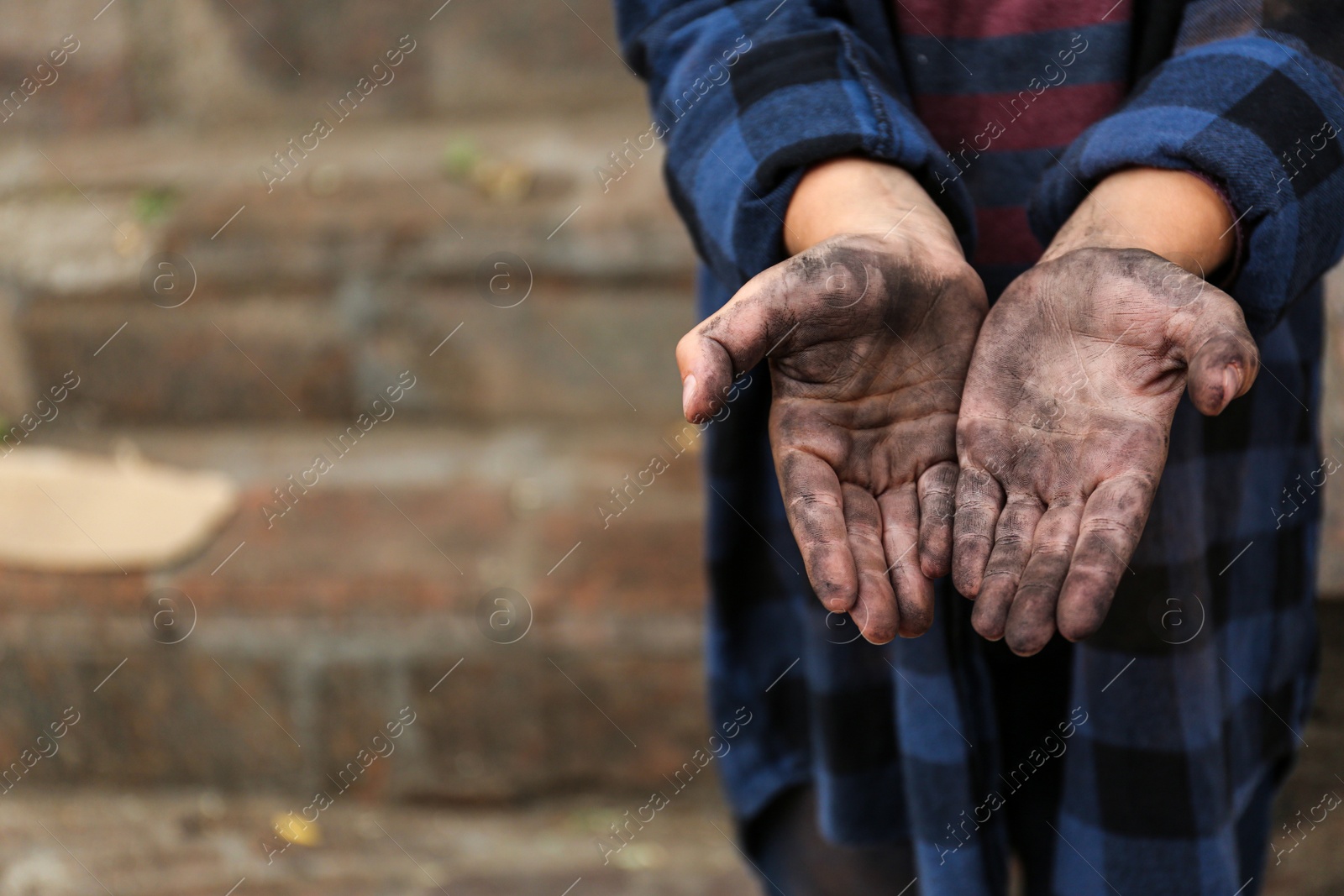 Photo of Poor homeless child begging for help outdoors, closeup