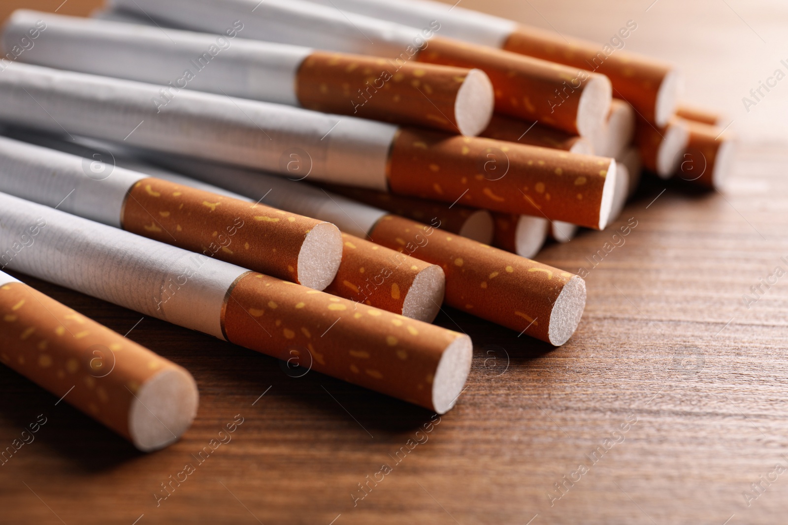 Photo of Pile of cigarettes on wooden table, closeup