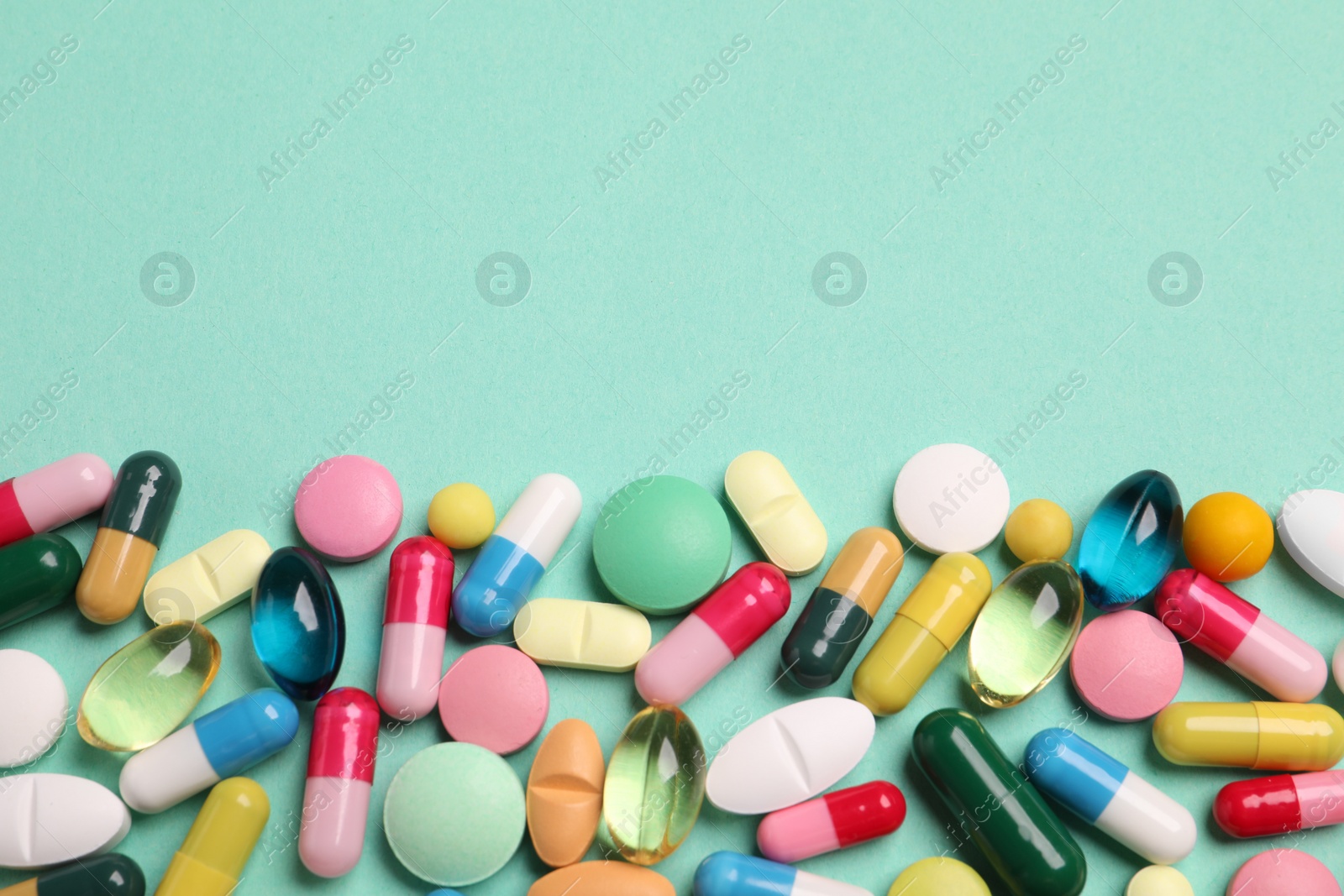 Photo of Many different pills on turquoise background, flat lay. Space for text