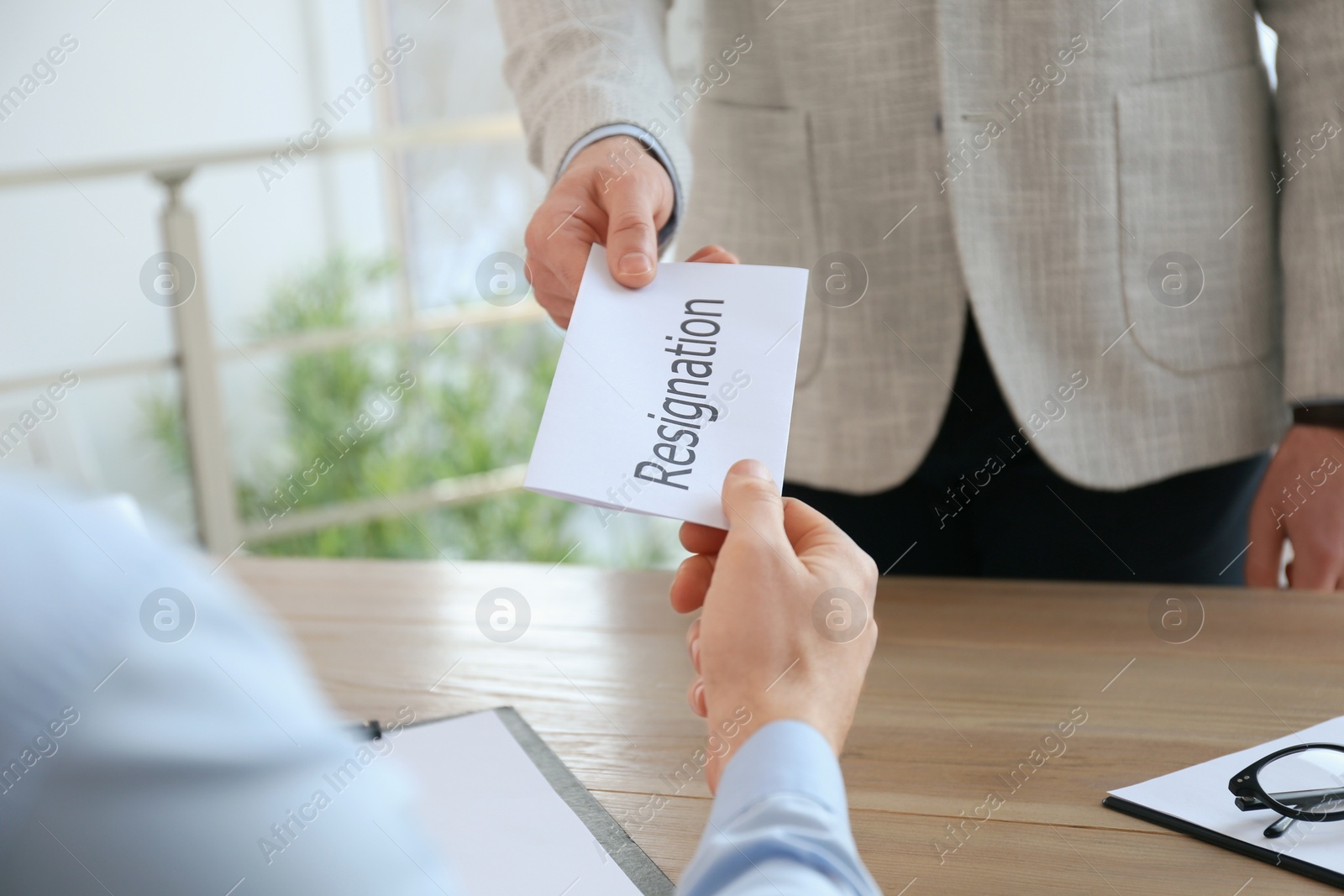 Photo of Employee giving resignation letter to boss in office, closeup