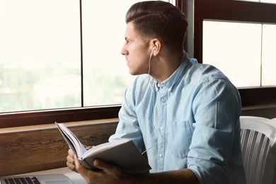 Photo of Man listening to audiobook at table in cafe