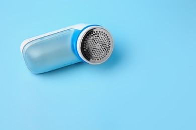 Photo of Modern fabric shaver on light blue background. Space for text