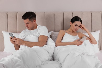 Internet addiction. Couple with smartphones in bed indoors