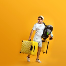 Photo of Male tourist with travel backpack and suitcases on yellow background