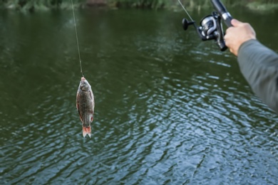 Man with rod fishing at riverside, closeup. Recreational activity