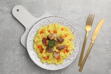 Photo of Delicious pilaf with meat served on light grey table, flat lay