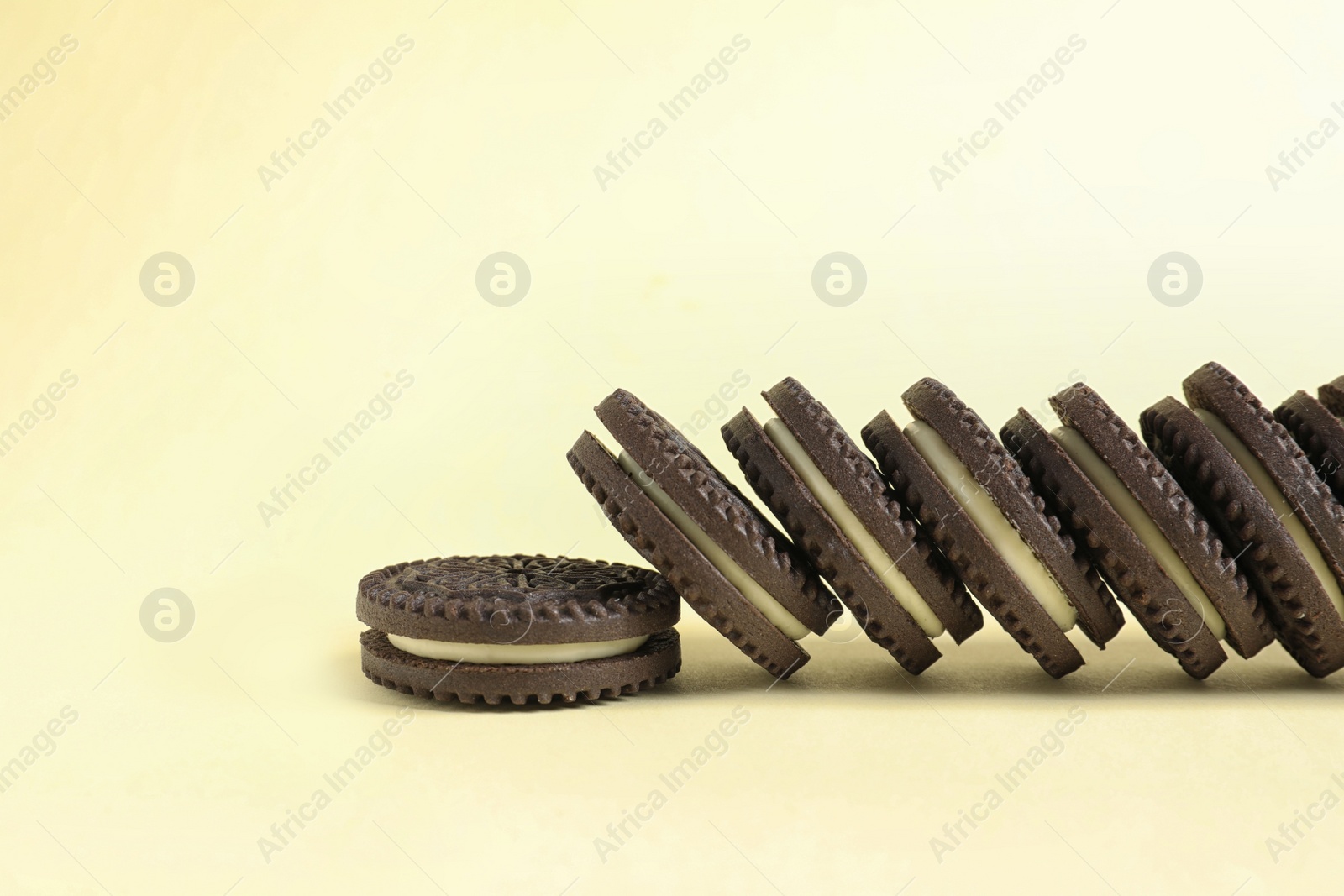 Photo of Tasty chocolate cookies with cream on color background. Space for text