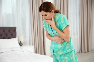 Photo of Young pregnant woman suffering from morning sickness at home. Space for text
